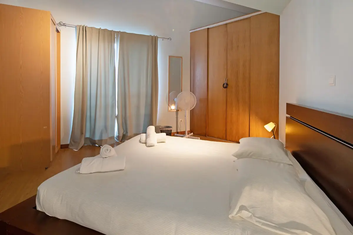 Cozy double bedroom with white bedding, grey pillows, dark wood headboard, and a modern art painting at Guest House da Fajã de Baixo