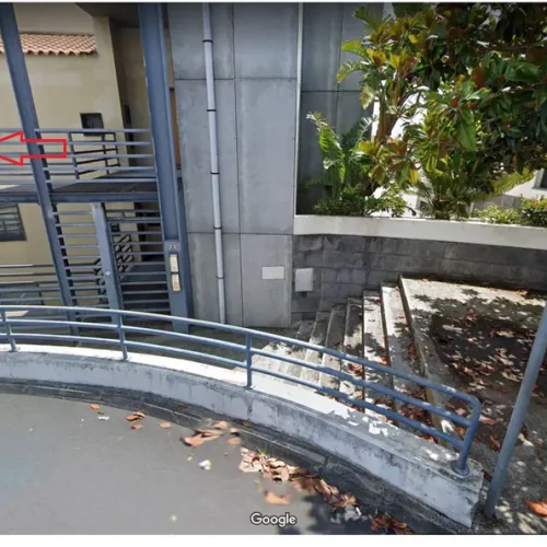 EN: Exterior pedestrian walkway and stairs leading to the first floor of the Ponta Delgada Apartment T3 complex, featuring secure blue metal railings. PT: Passadiço pedonal exterior e escadas de acesso ao primeiro piso do complexo Ponta Delgada Apartment T3, com guardas metálicas de segurança azuis.