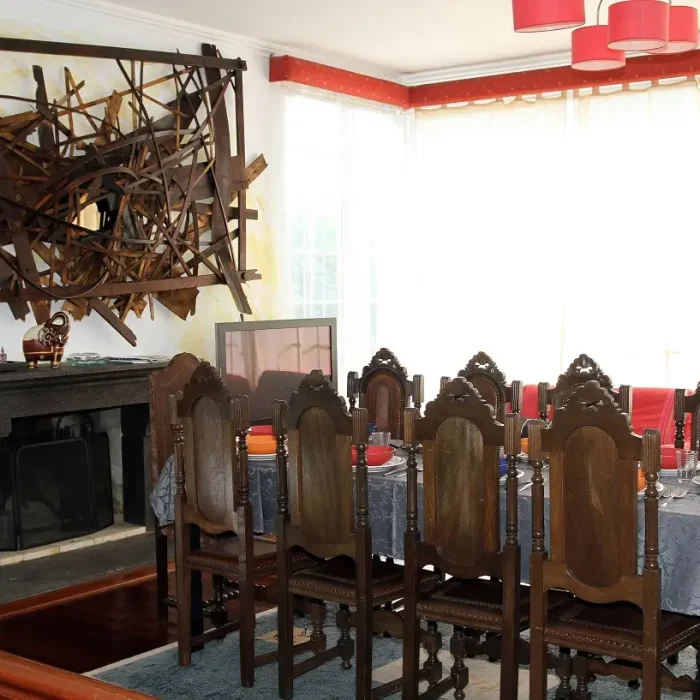 Spacious living room with fireplace, rustic wooden art installation, dining table and TV at São Miguel Ponta Delgada vacation house